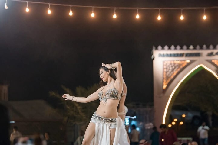 Under the shimmering lights immerse yourself in the magic of traditional dance where the rhythms of the desert come alive creating unforgettable memories amidst the enchanting surroundings.